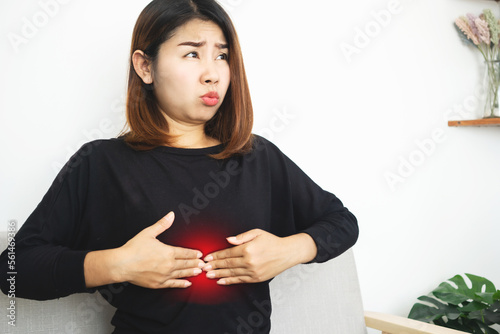 Asian woman suffering from Epigastric pain caused by acid indigestion, GERD or too much gas in the stomach photo