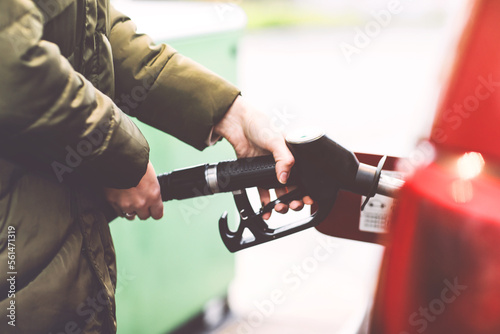 Close-up of hands of woman at self-service gas station  hold fuel nozzle and refuel the car with petrol  diesel  gas. Close up of filling auto with gasoline or benzine. Self service gas pump