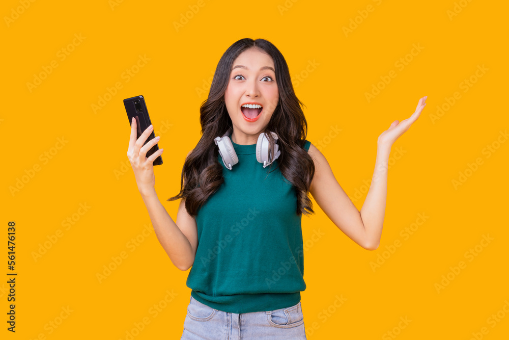 exited surprise face expression asian young woman female hand gesture exited with big good news on smartphone screen display exited raised hands up isolated on bright yellow colour exited surprise face expression asian young woman female hand gesture exited with big good news on smartphone screen display exited raised hands up isolated on bright yellow colour