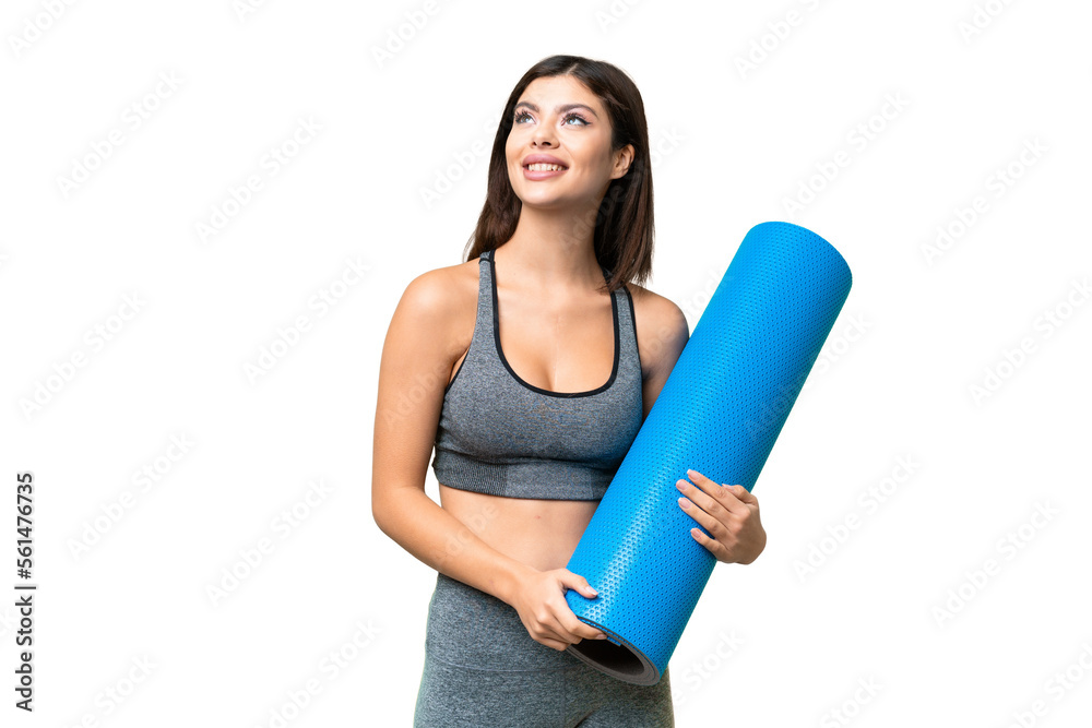 Young sport woman going to yoga classes while holding a mat over isolated chroma key background thinking an idea while looking up Young sport woman going to yoga classes while holding a mat over isolated chroma key background thinking an idea while looking up