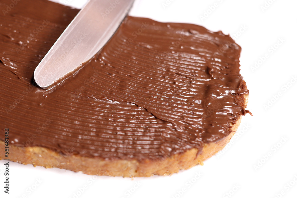 Knife smears a piece of bread, toast with chocolate cream, isolated on white background, selective focus Knife smears a piece of bread, toast with chocolate cream, isolated on white background, selective focus