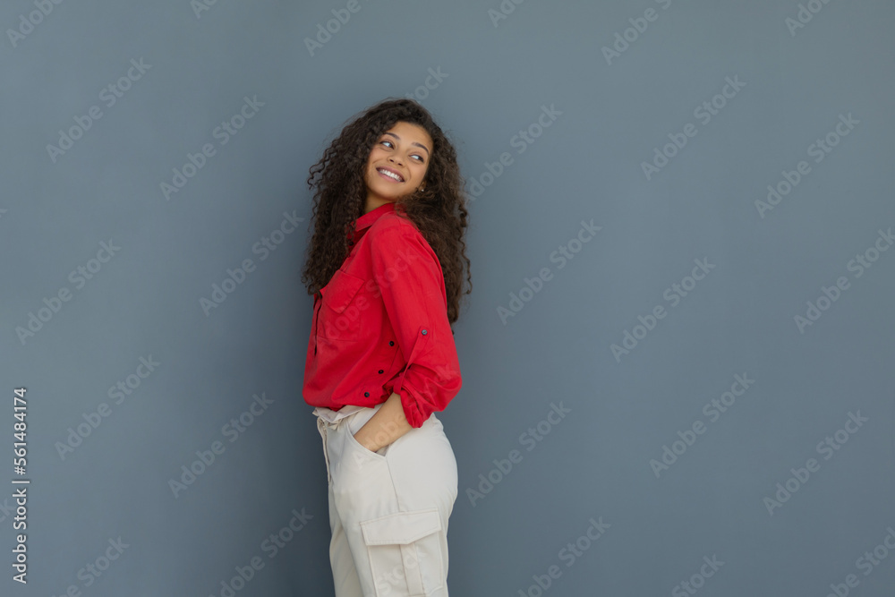 Young woman in red shirt standing against grey wall Young woman in red shirt standing against grey wall