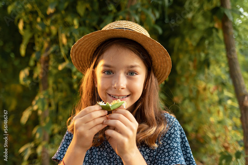 Exotic fresh fruit. Portrait of happy cute little girl in a straw hat eating a passion fruit. Slow motion. Concept of organic gardening and home agriculture
