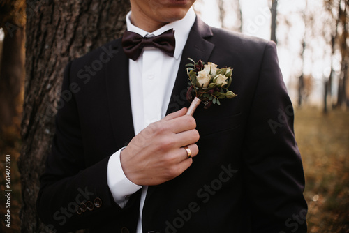 The groom in a suit corrects a flower