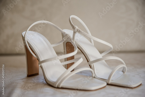 A pair of white women's sandals over light background. Female high heel summer shoes.