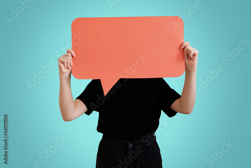 Photo young woman holding speech balloon orange poster covering her face isolated on blue background in studio mockup for design. space for text