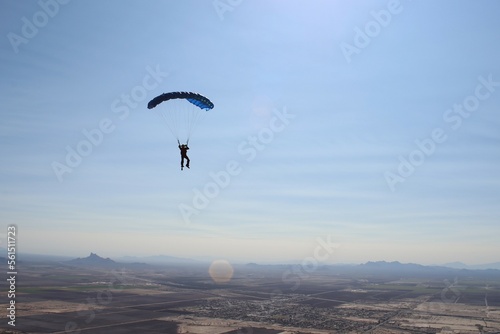 Skydive flys parachute over Arizona on a beautiful sunny afternoon with mountains in the background.