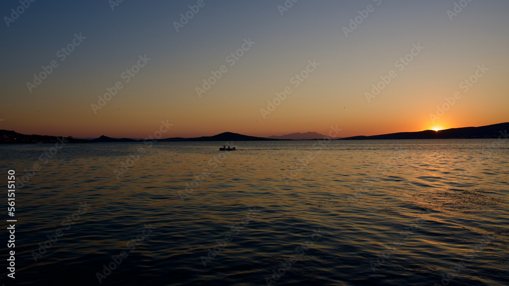 Sea and Cunda island in the evening. The lights of the excursion boats are reflected in the sea. Night sea and lights.