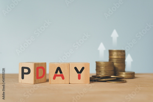 pay day loan concept, pay day text on wooden cube block and blurred stack of coins and blurred arrow up above