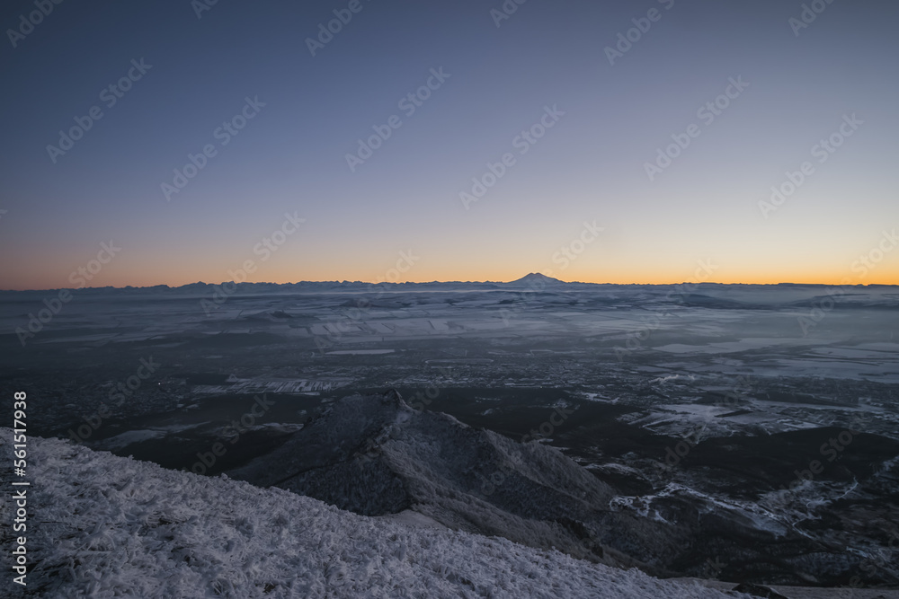 Panorama from Mount Beshtau to the city, a winter landscape in the evening at sunset, a panorama with icy and snow-covered trees on the mountainside