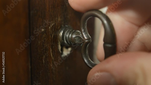 caucasian man's hand using antique key and open a wood door. photo