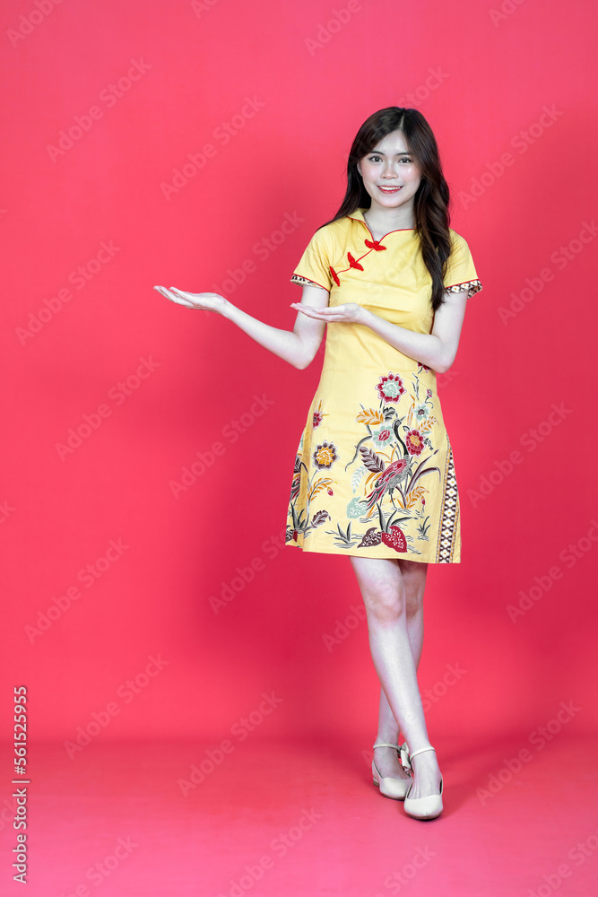 A beautiful asian woman presenting to her side while wearing simple yellow chinese dress A beautiful asian woman presenting to her side while wearing simple yellow chinese dress