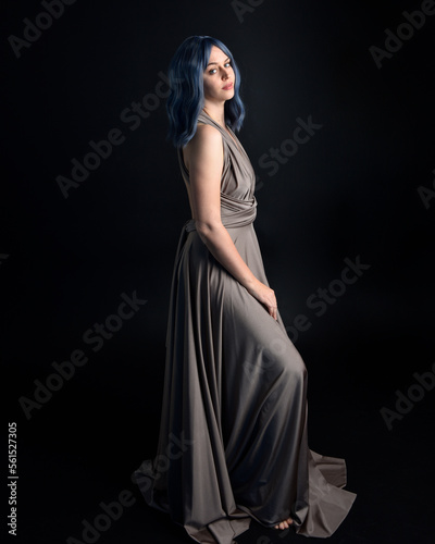  close up portrait of pretty girl with blue hair wig & elegant gown with expressive facial expressions & gestural arm poses. colourful neon gel lighting, isolated on studio background.