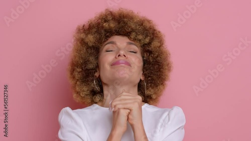 Woman beg with cute smile, she asks for help, cute curly haired female, next to pink wall