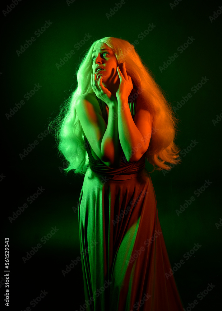 portrait of pretty girl with blonde hair & elegant gown with expressive facial expressions & gestural arm poses. colourful neon gel lighting, isolated on black studio background.