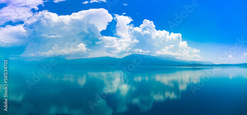 Panorama of clouds float across the daytime sky above the horizon with the Adriatic Sea in the light of the sun