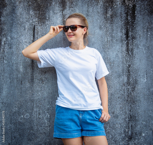 Female model wearing white blank t-shirt on the background of an gray scratched wall.