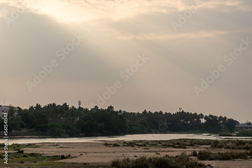 Crepuscular sun rays through overcast clouds above the Cauvery river in Trichy.