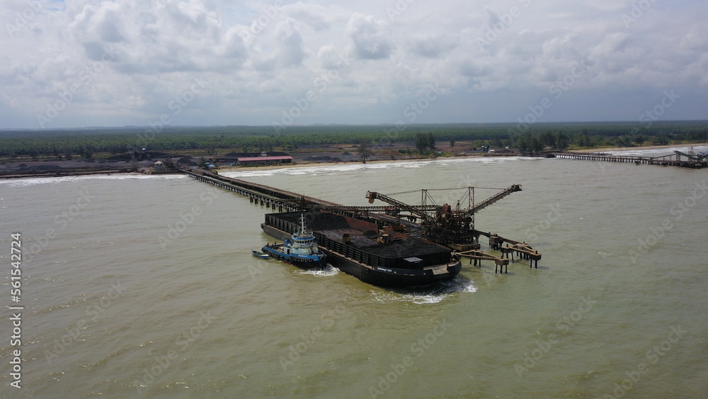 Obraz premium Aerial view of the activity loading coal into barges in a shipyard