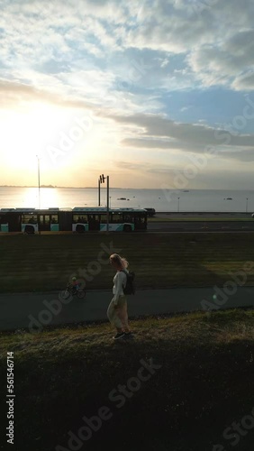 Vertical video: person walking on the road near to beach on sunset