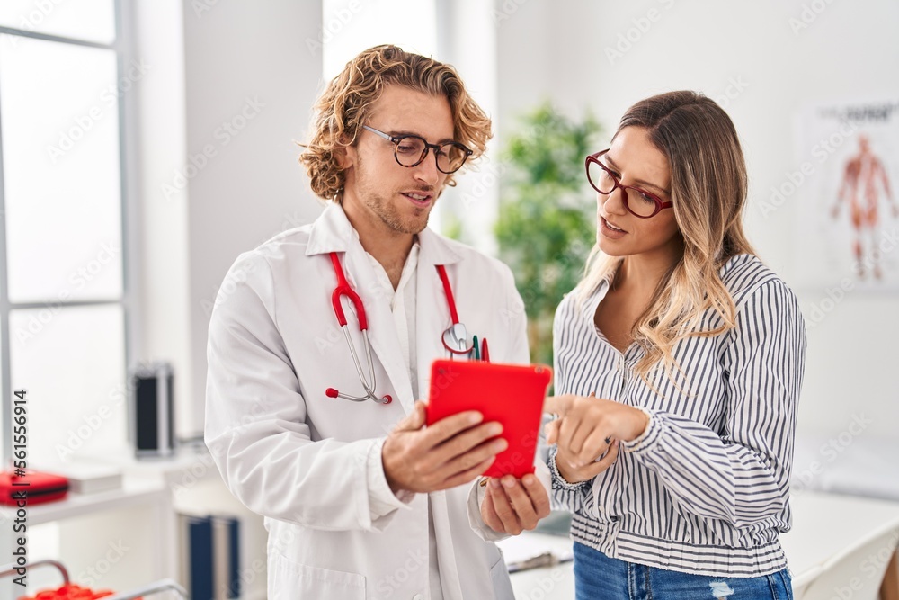Man and woman doctor and patient having medical consultation using touchpad at clinic Man and woman doctor and patient having medical consultation using touchpad at clinic