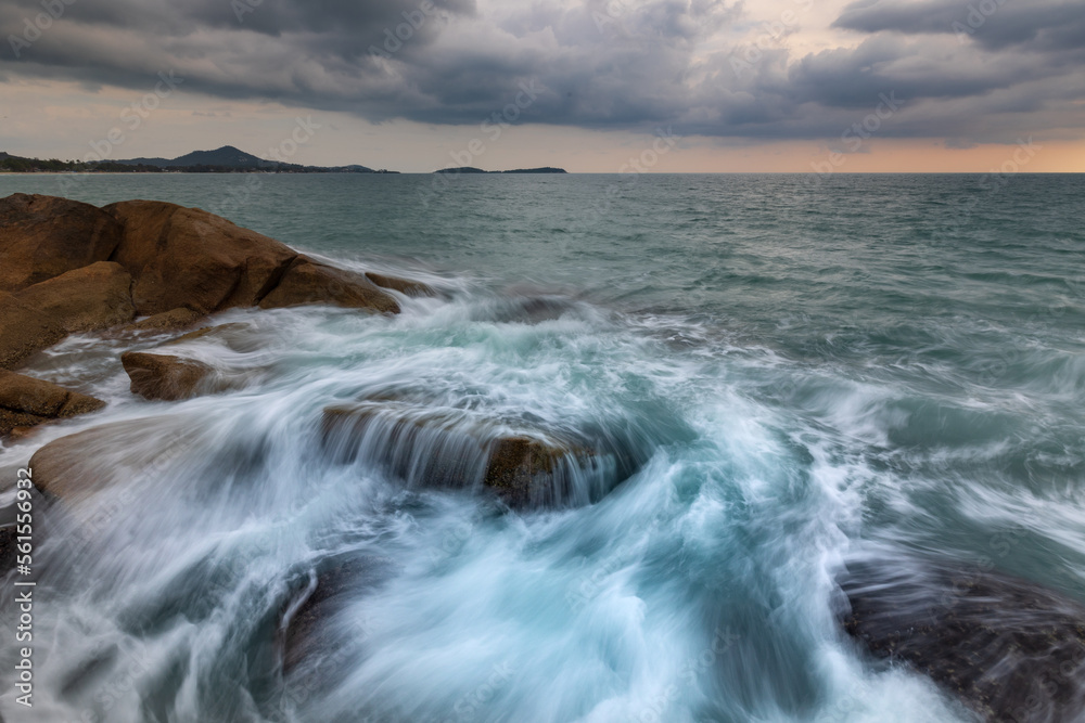 Artistic seascape with blurry waves crashing against granite rocks on the shore, Samui, Thailand