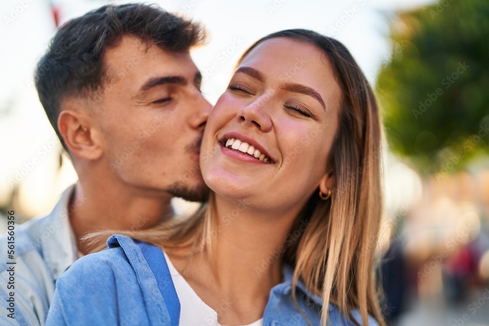 Young man and woman couple hugging each other and kissing standing at street Young man and woman couple hugging each other and kissing standing at street