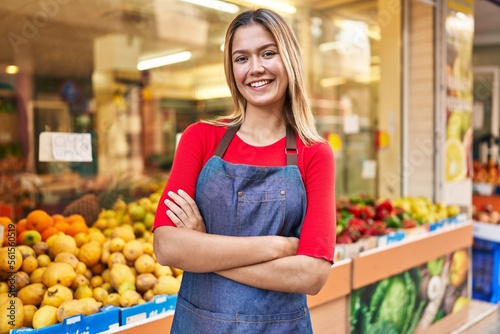 Young hispanic woman shop assistant standing with arms crossed gesture at fruit market photo