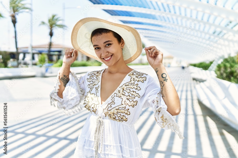 Young hispanic woman smiling confident wearing summer hat at street