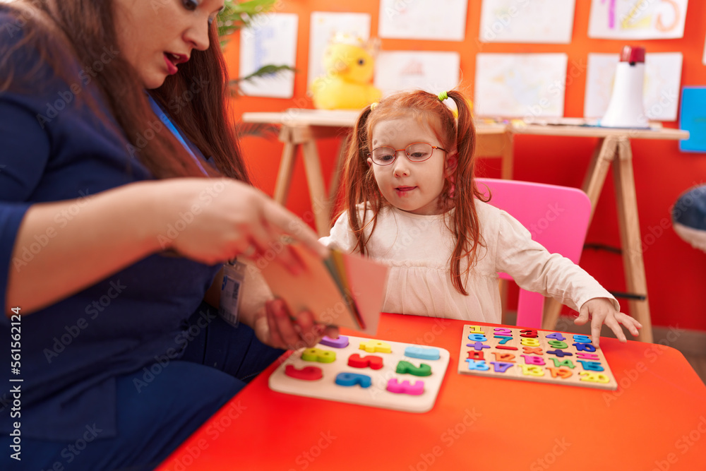 Fototapeta premium Teacher and student playing with maths puzzle game looking cards at kindergarten