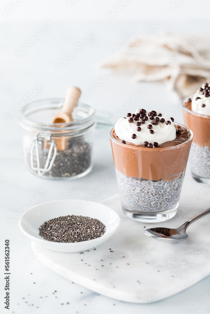 A chocolate mousse chia pudding with chia seeds in front and to the side. A chocolate mousse chia pudding with chia seeds in front and to the side.