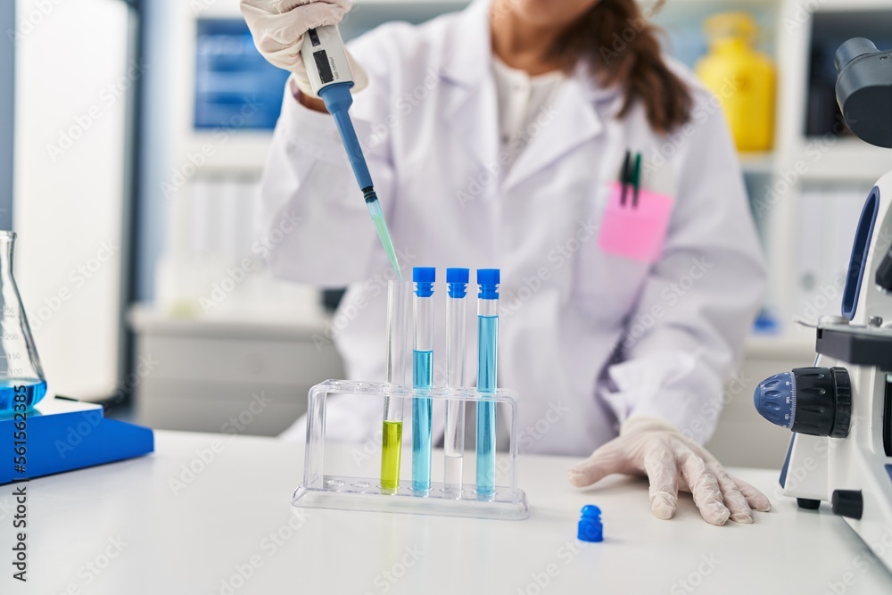Young latin woman wearing scientist uniform using pipette working at laboratory Young latin woman wearing scientist uniform using pipette working at laboratory