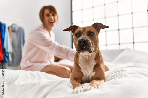 Young caucasian woman smiling confident sitting on bed with dog at bedroom