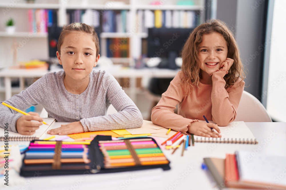 Two kids students sitting on table drawing on notebook paper at classroom Two kids students sitting on table drawing on notebook paper at classroom
