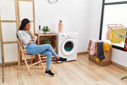 Obraz na plátně Young latin woman bored waiting for washing machine at laundry room