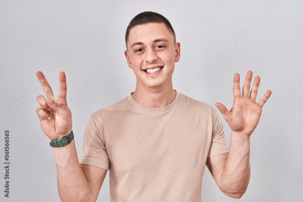 Fototapeta premium Young man standing over isolated background showing and pointing up with fingers number seven while smiling confident and happy.