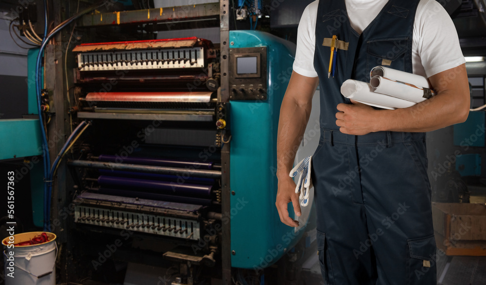 Man working in printing house with paper and printing machine Man working in printing house with paper and printing machine