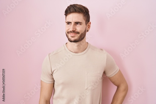 Hispanic man with beard standing over pink background smiling looking to the side and staring away thinking. © Krakenimages.com