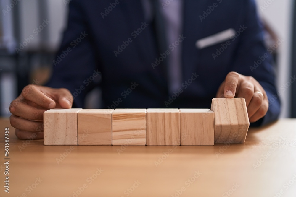 Young latin man business worker sitting on table with wooden cubes at office Young latin man business worker sitting on table with wooden cubes at office
