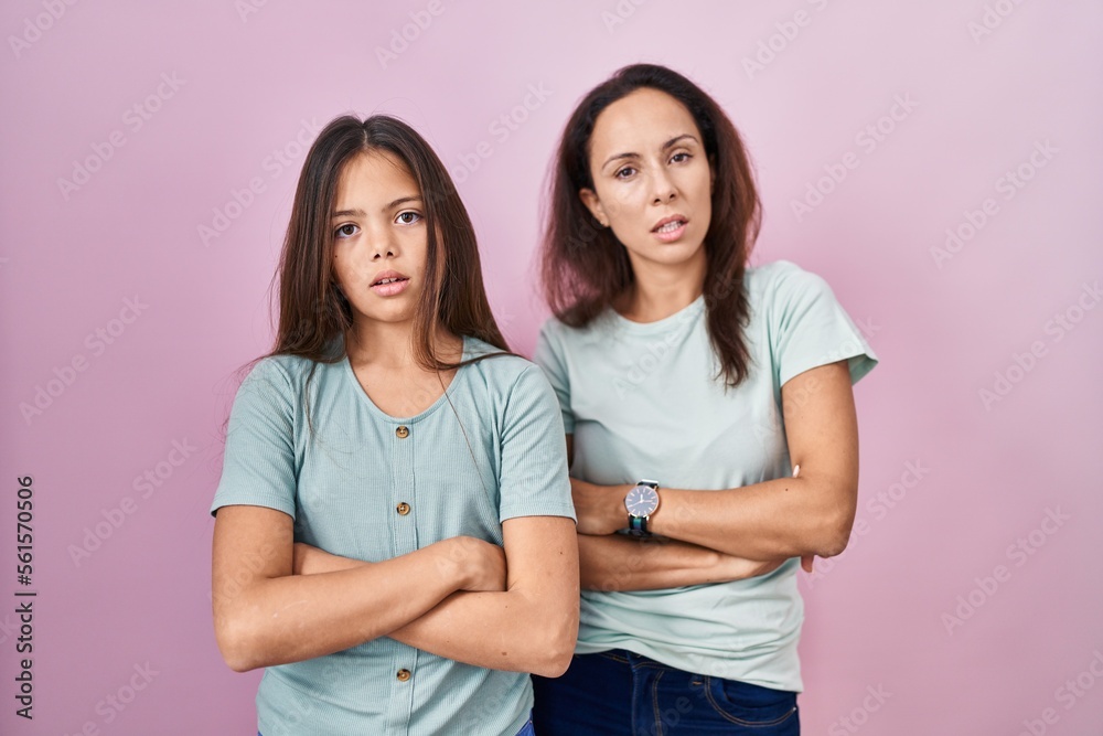Young mother and daughter standing over pink background skeptic and nervous, disapproving expression on face with crossed arms. negative person. Young mother and daughter standing over pink background skeptic and nervous, disapproving expression on face with crossed arms. negative person.