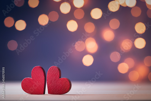 Saint Valentine day greeting card with two red hearts against festive bokeh background.