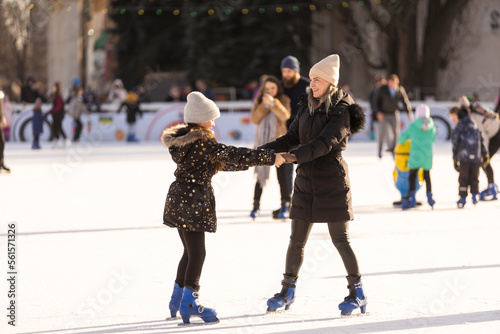 Mother and daughter skateing on ice.