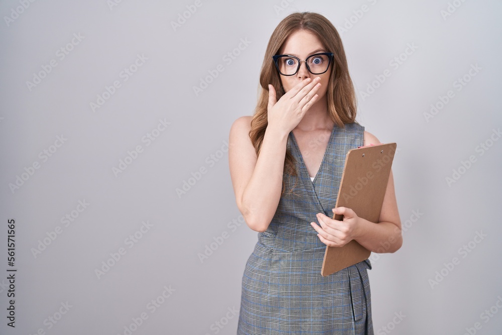Caucasian woman wearing glasses and business clothes shocked covering mouth with hands for mistake. secret concept. Caucasian woman wearing glasses and business clothes shocked covering mouth with hands for mistake. secret concept.