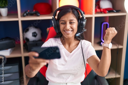 Fotografia, Obraz Young hispanic woman playing video games with smartphone screaming proud, celebr