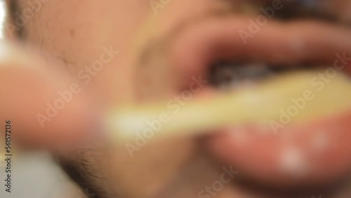 close-up man brush teeth in a blur bathroom background.