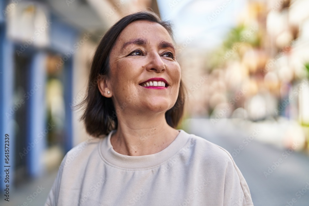 Middle age woman smiling confident looking to the sky at street