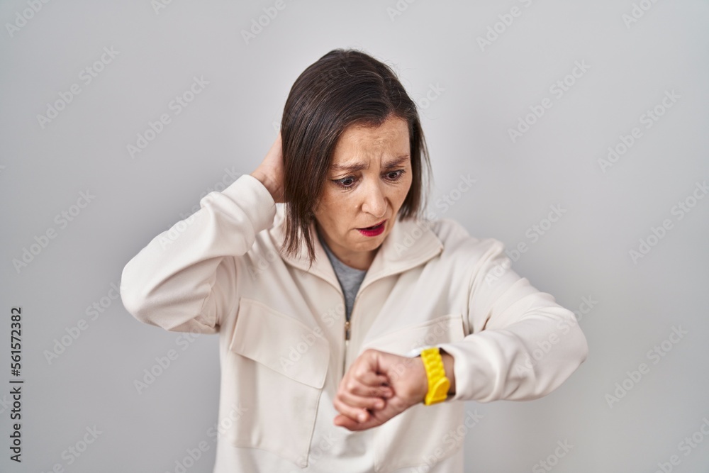 Middle age hispanic woman standing over isolated background looking at the watch time worried, afraid of getting late Middle age hispanic woman standing over isolated background looking at the watch time worried, afraid of getting late