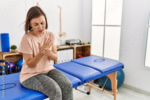 Middle age hispanic woman with hand pain at physiotherapy clinic