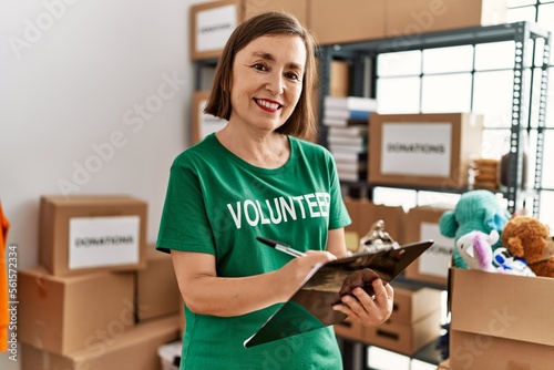 Middle age hispanic woman checking donations on checklist at donations stand