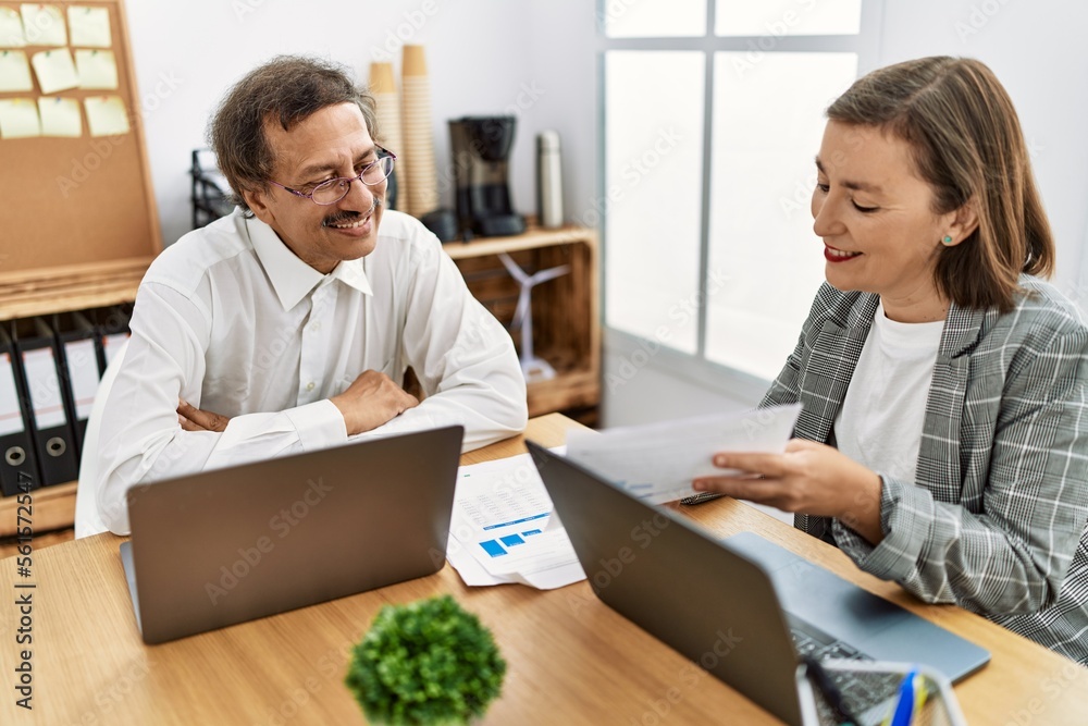 Middle age man and woman business workers using laptop and document working at office Middle age man and woman business workers using laptop and document working at office